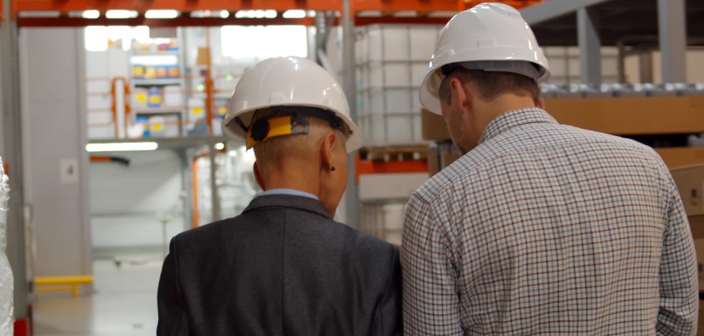 Photograph of managers from behind as they observe warehouse floor operations 